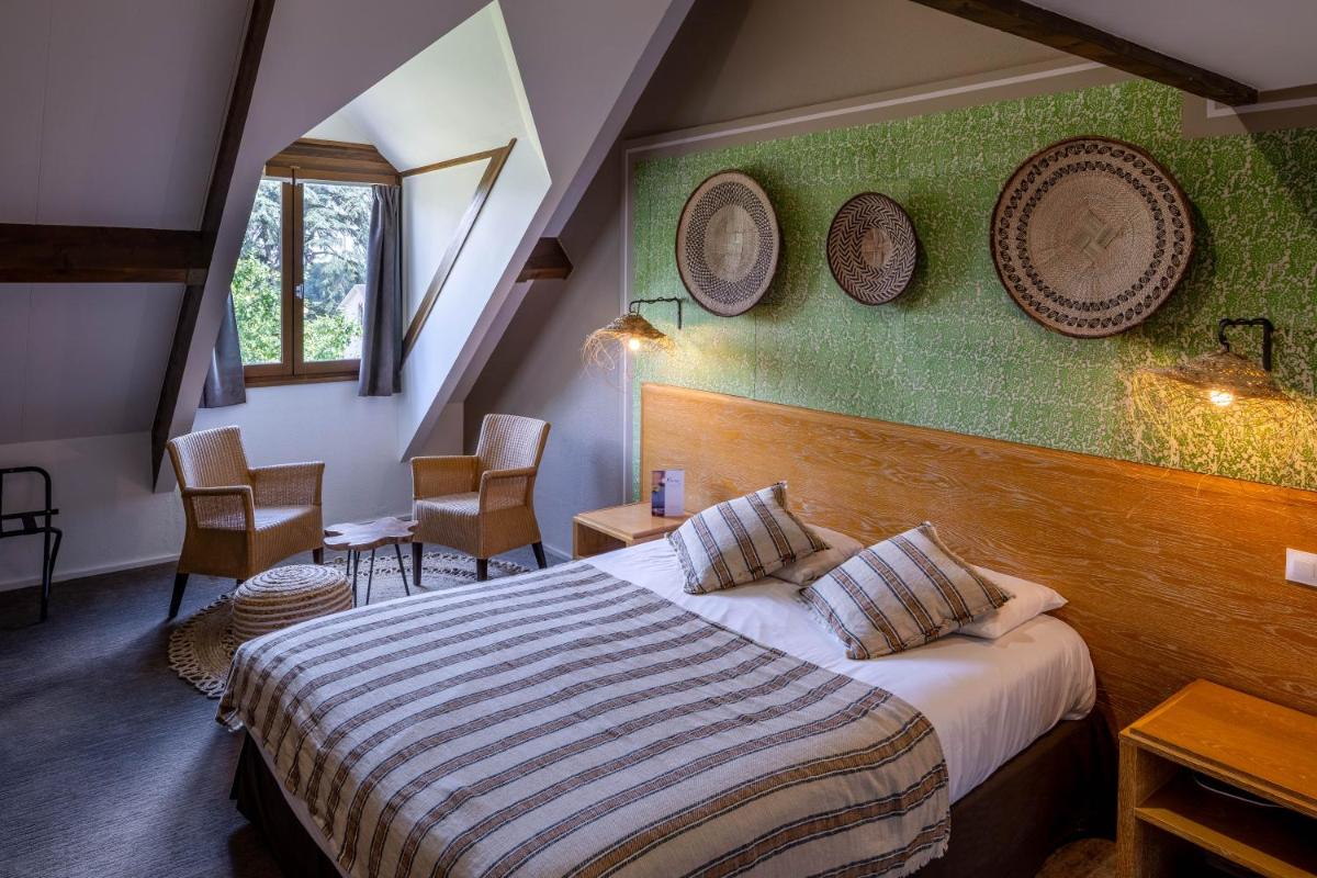 une chambre d'hôtel avec un lit et deux assiettes accrochées au mur dans l'établissement Garrigae Manoir de Beauvoir Poitiers Sud - Hotel & Spa, à Mignaloux-Beauvoir
