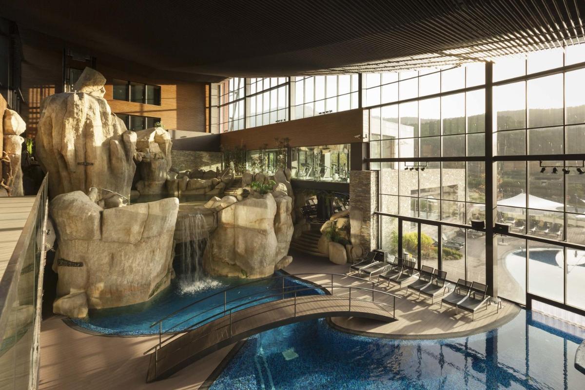 uma vista para um resort com uma piscina e uma cascata em H2otel Congress & Medical SPA em Unhais da Serra