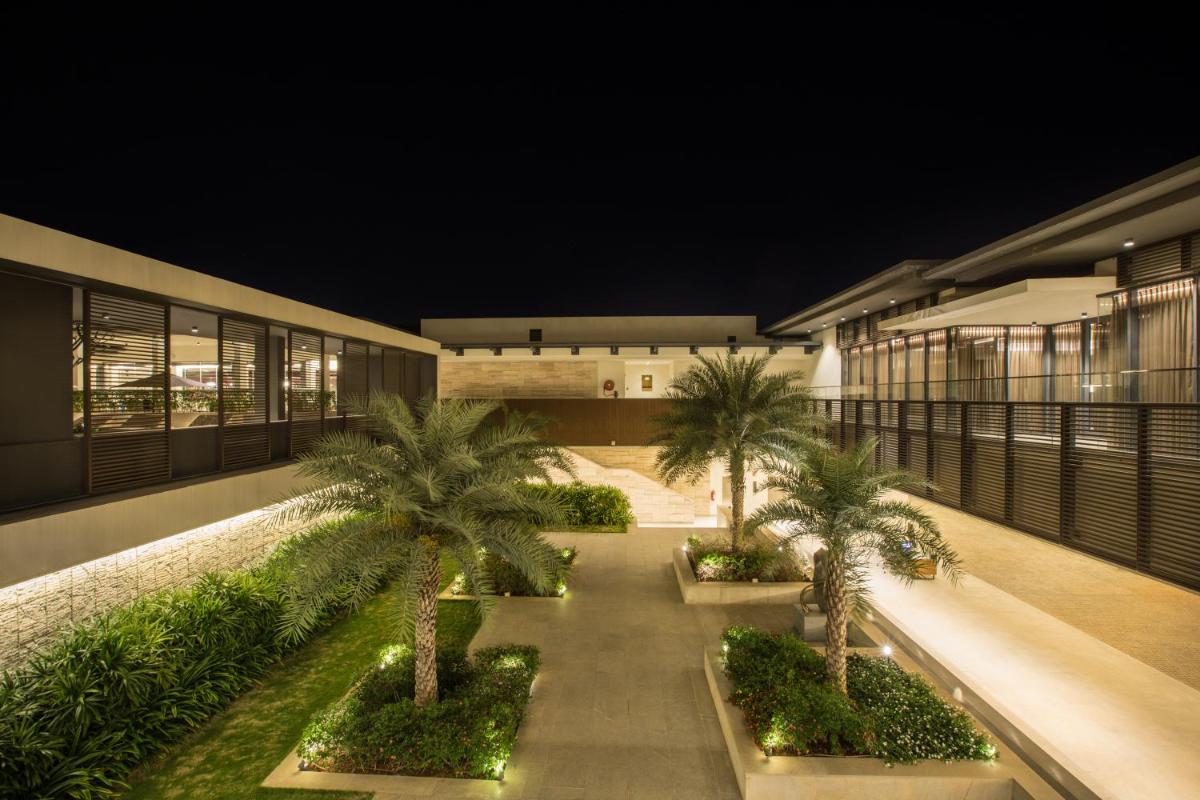 a courtyard with palm trees on a building at night at BLVD Club - Near BENGALURU AIRPORT in Bengaluru