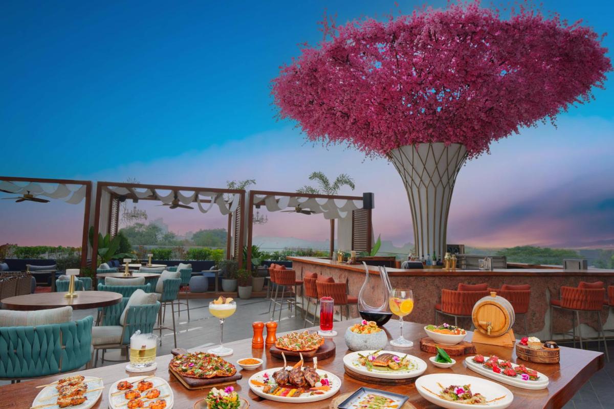 a table with plates of food and a vase of flowers at The Westin Pune Koregaon Park in Pune