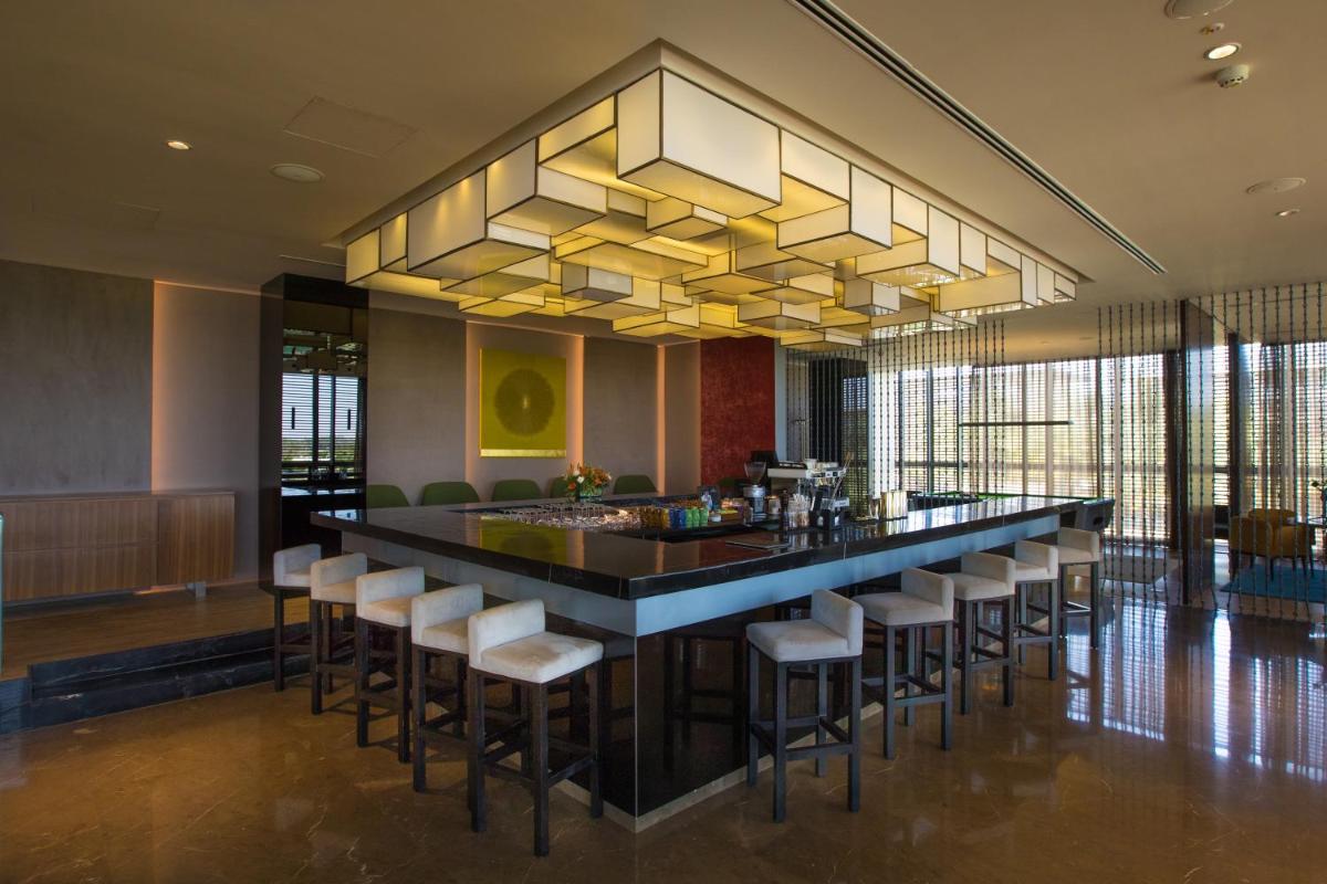 a bar with stools in a lobby with a chandelier at BLVD Club - Near BENGALURU AIRPORT in Bengaluru