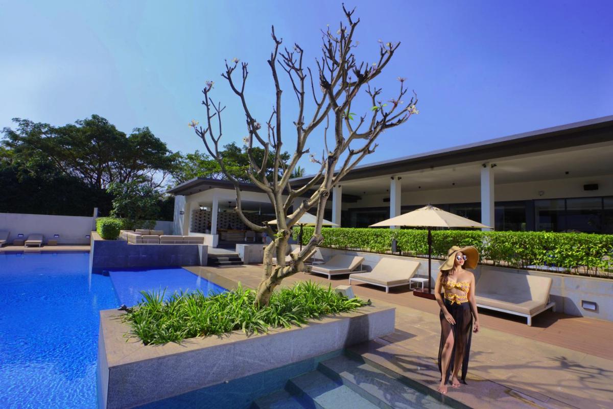 a woman is standing next to a swimming pool at BLVD Club - Near BENGALURU AIRPORT in Bengaluru