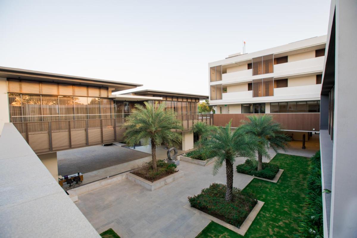 a courtyard with palm trees in front of a building at BLVD Club - Near BENGALURU AIRPORT in Bengaluru