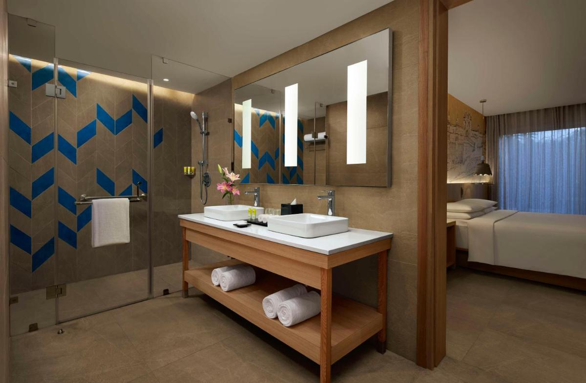 a bathroom with a sink and a mirror and a bed at Hyatt Place Jaipur Malviya Nagar in Jaipur a bathroom with a sink and a mirror and a bed at Hyatt Place Jaipur Malviya Nagar in Jaipur