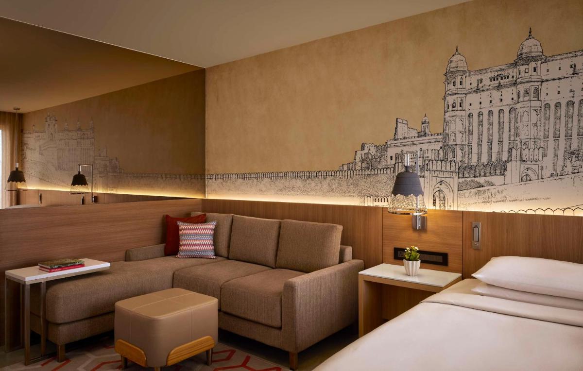 a hotel room with a couch and a bed at Hyatt Place Jaipur Malviya Nagar in Jaipur a hotel room with a couch and a bed at Hyatt Place Jaipur Malviya Nagar in Jaipur