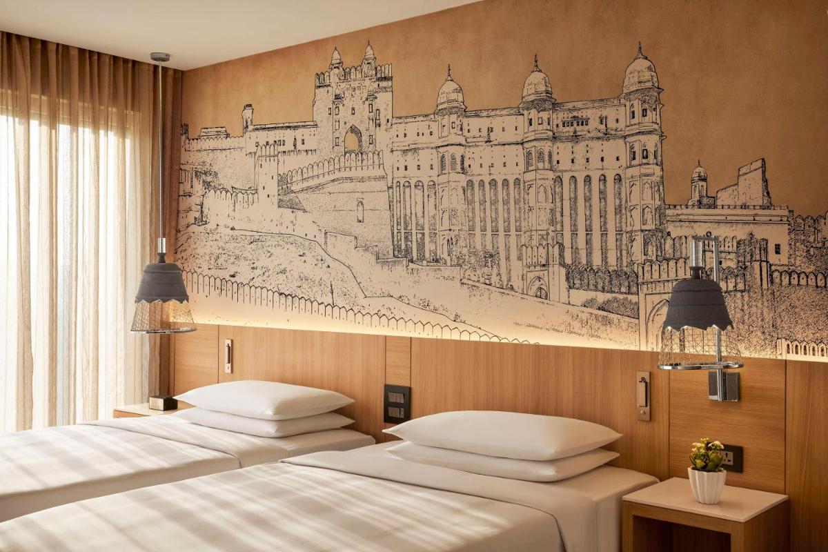 two beds in a room with a drawing on the wall at Hyatt Place Jaipur Malviya Nagar in Jaipur two beds in a room with a drawing on the wall at Hyatt Place Jaipur Malviya Nagar in Jaipur