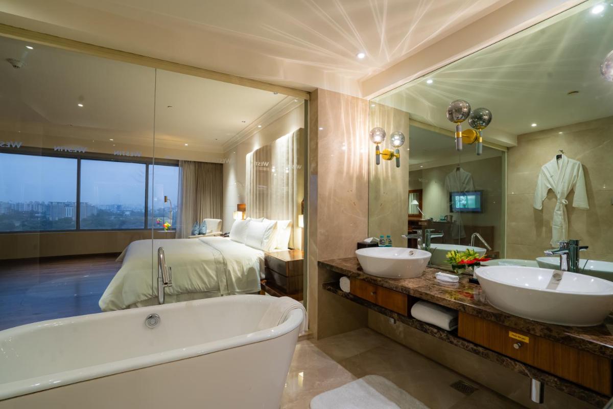 a bathroom with two sinks and a tub and a bed at The Westin Pune Koregaon Park in Pune