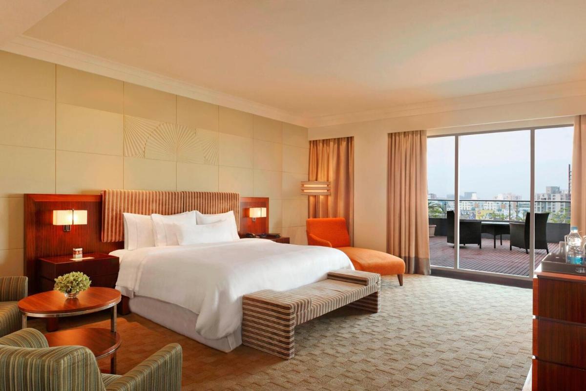 a hotel room with a large bed and a balcony at The Westin Pune Koregaon Park in Pune