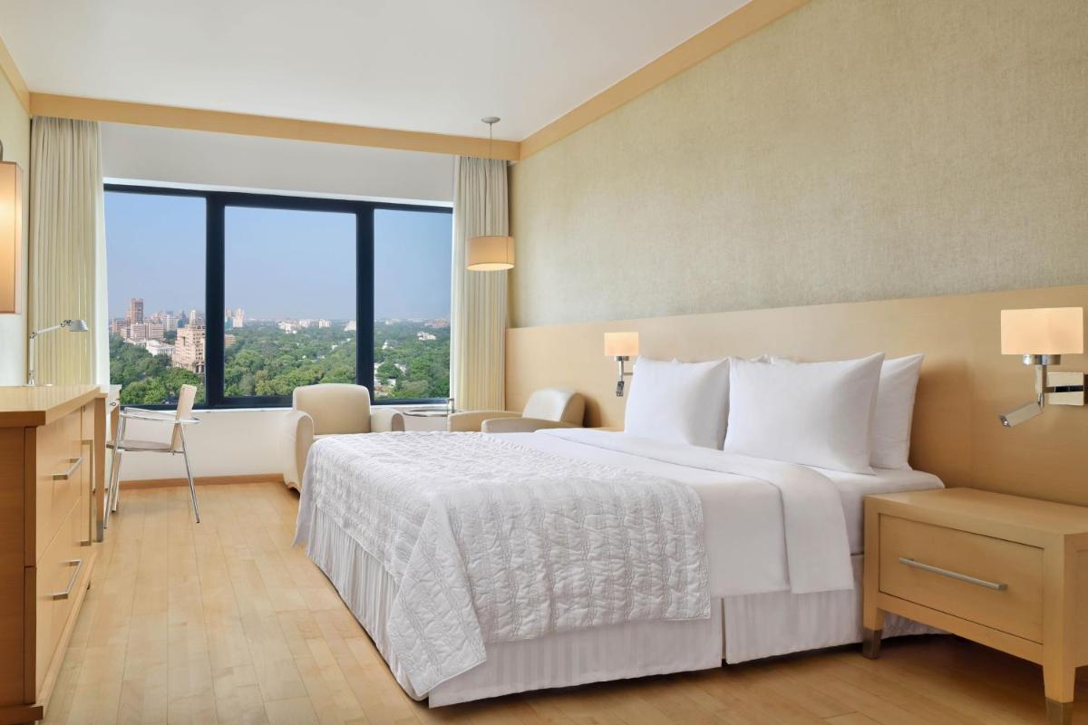 a hotel room with a bed and a large window at Le Meridien New Delhi in New Delhi a hotel room with a bed and a large window at Le Meridien New Delhi in New Delhi