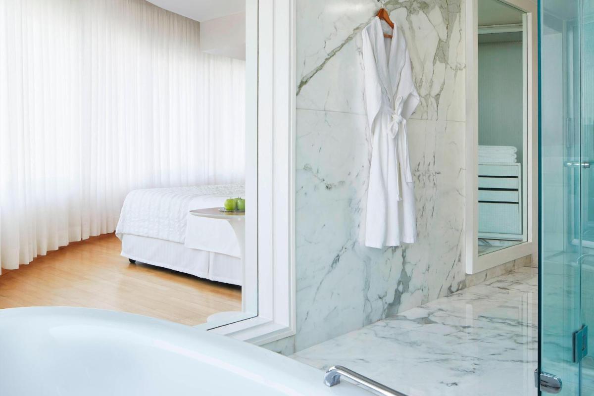 a bathroom with a bath tub and a bedroom at Le Meridien New Delhi in New Delhi a bathroom with a bath tub and a bedroom at Le Meridien New Delhi in New Delhi