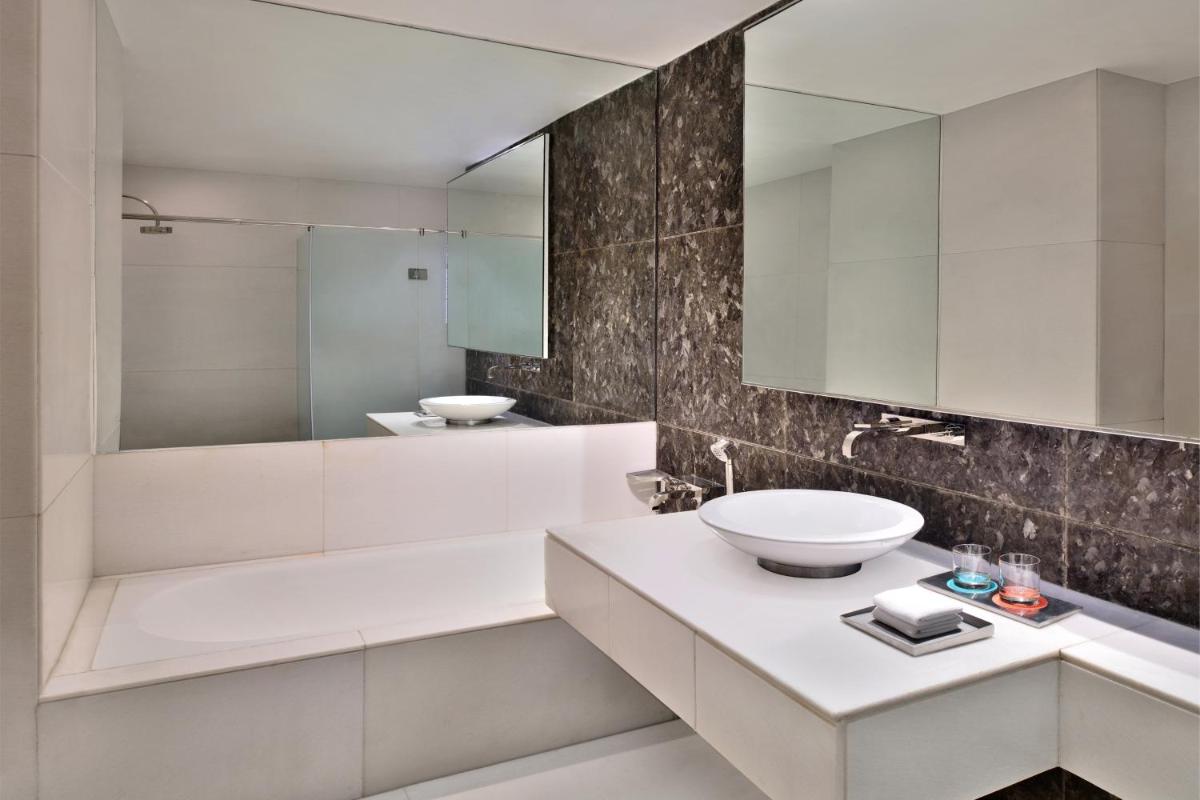a white bathroom with a sink and a mirror at Le Meridien New Delhi in New Delhi a white bathroom with a sink and a mirror at Le Meridien New Delhi in New Delhi