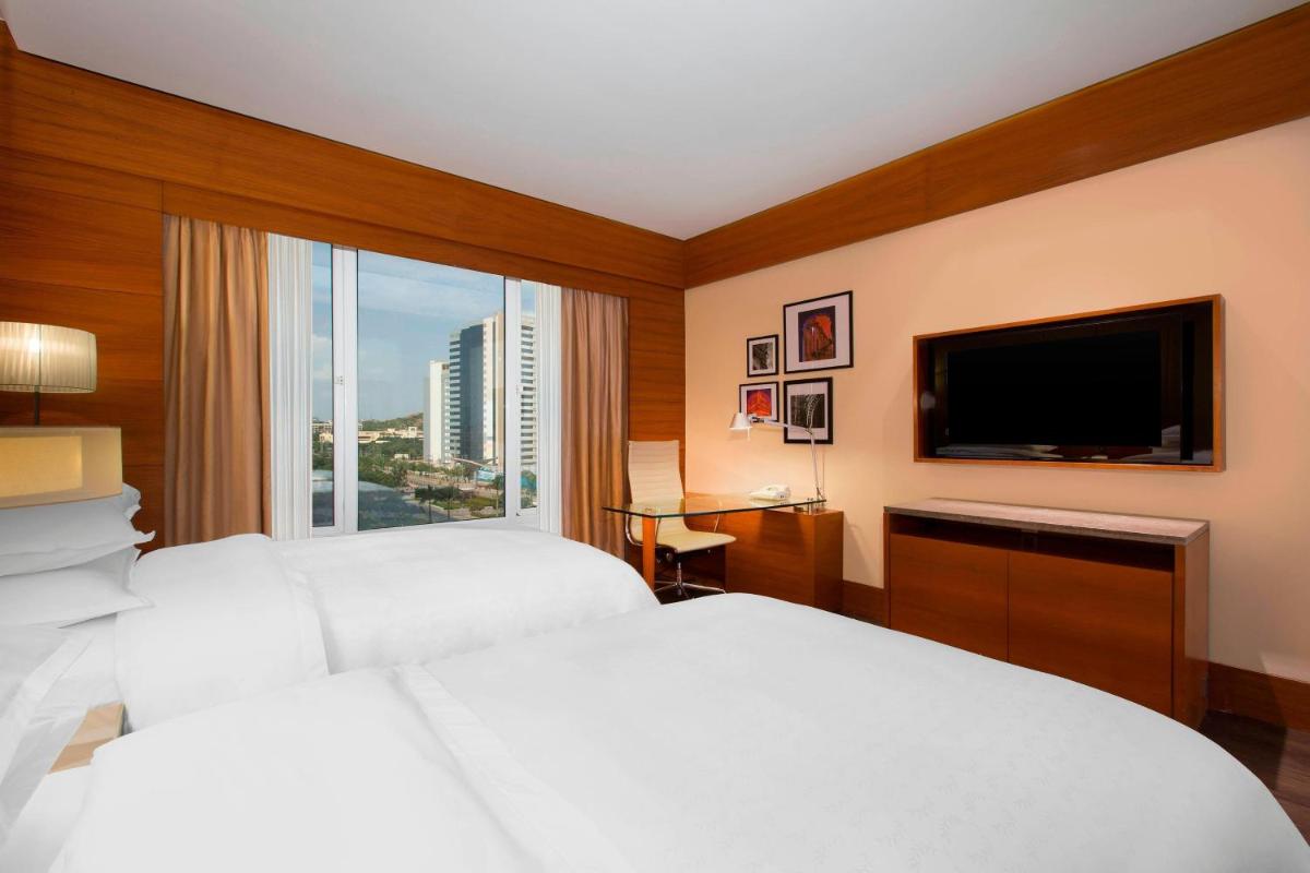 a hotel room with two beds and a flat screen tv at Sheraton Hyderabad Hotel in Hyderabad