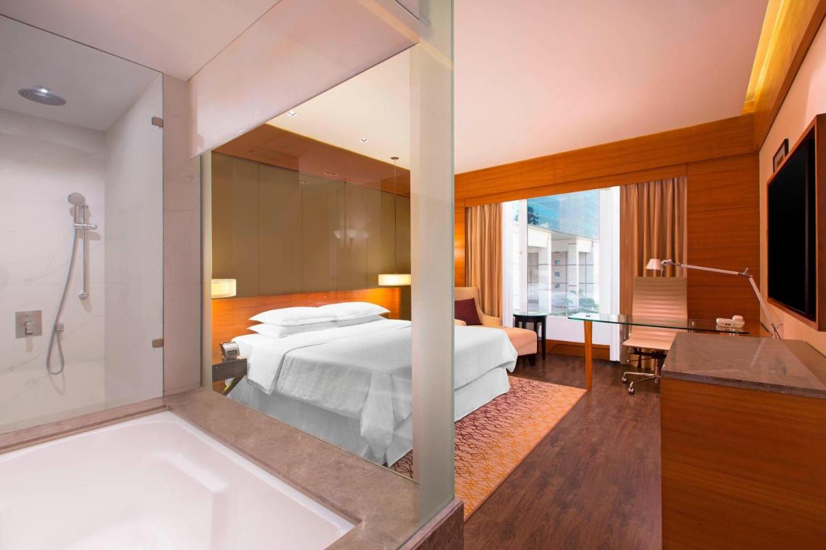 a hotel room with a bed and a bath tub at Sheraton Hyderabad Hotel in Hyderabad