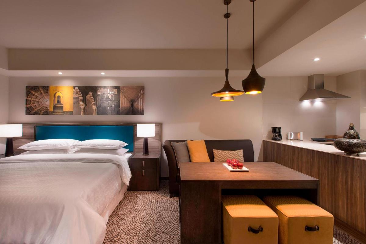 a bedroom with a bed and a desk and a table at Sheraton Hyderabad Hotel in Hyderabad