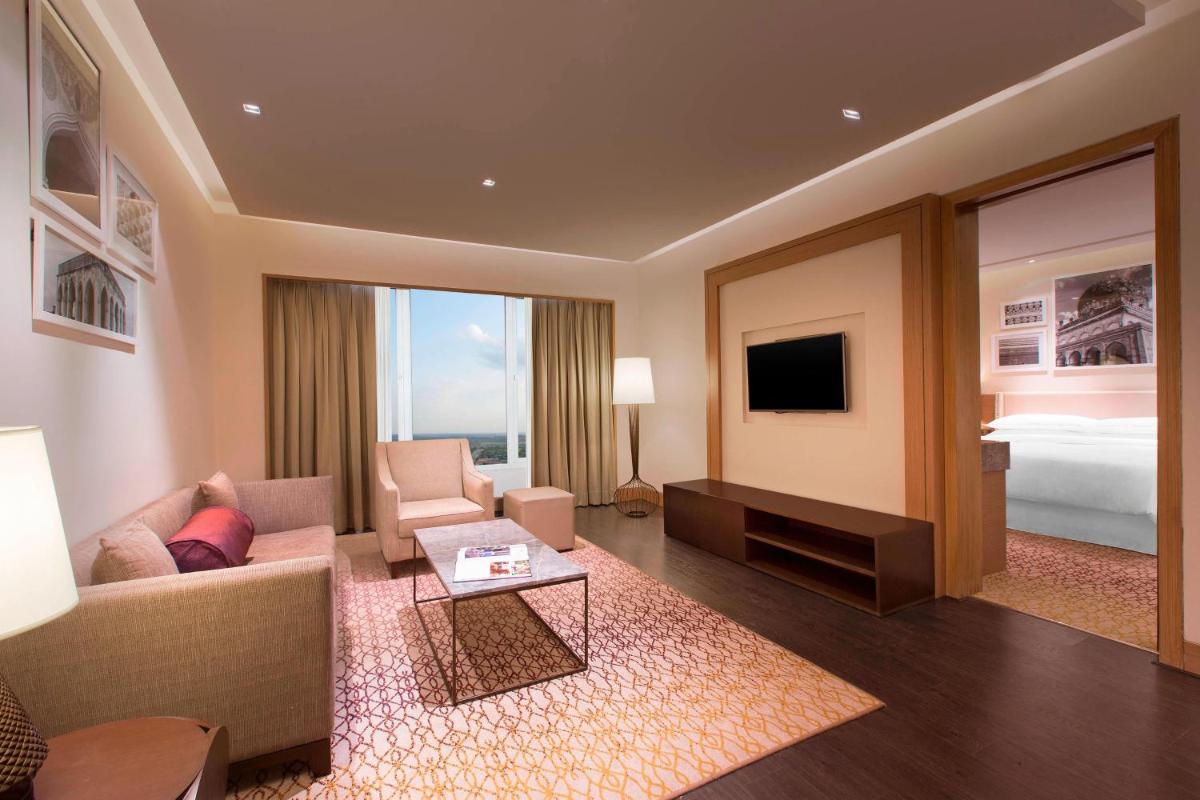 a living room with a couch and a tv at Sheraton Hyderabad Hotel in Hyderabad