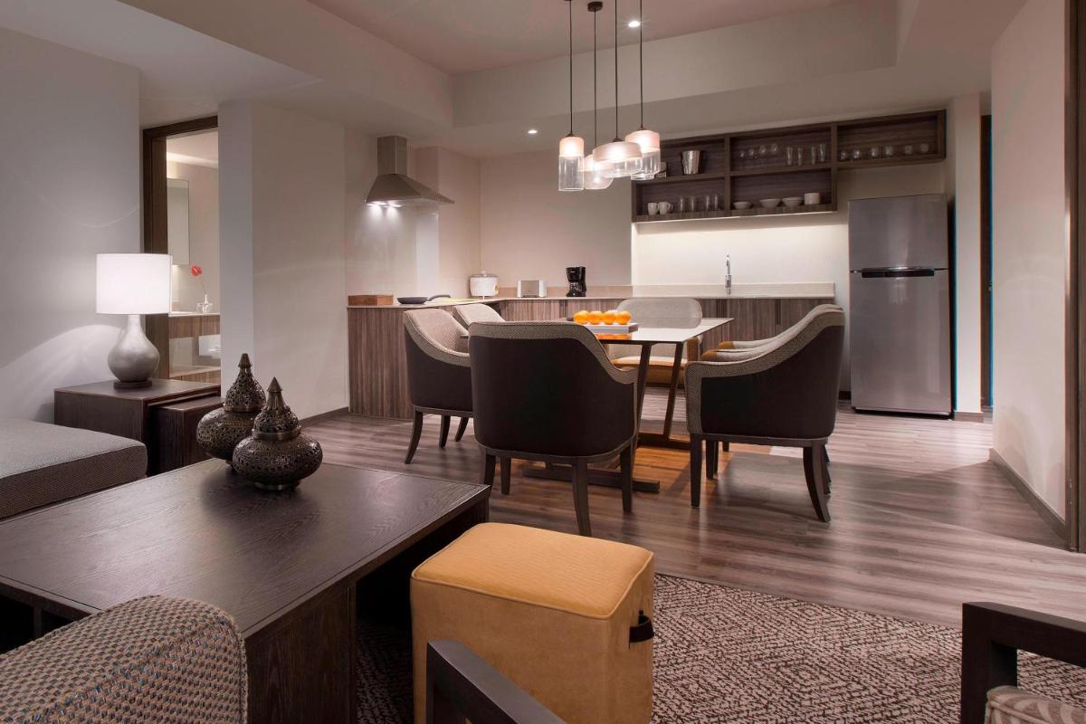 a living room and kitchen with a table and chairs at Sheraton Hyderabad Hotel in Hyderabad