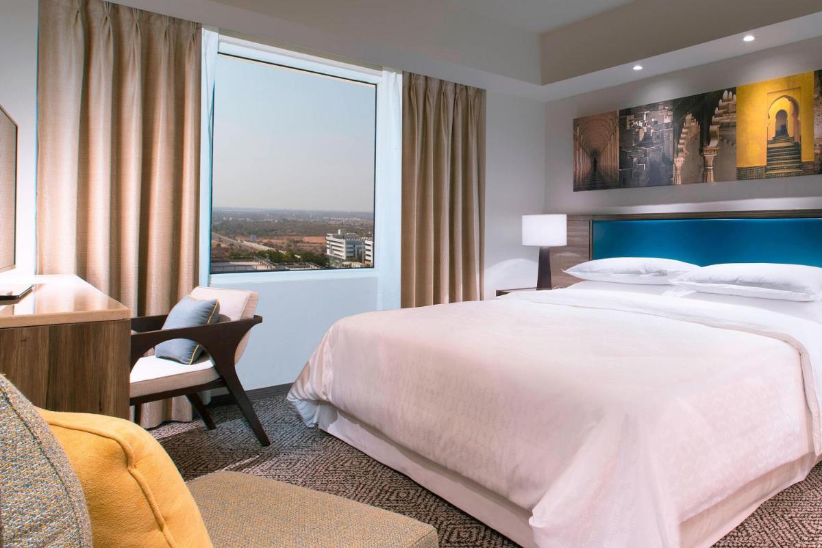 a hotel room with a large bed and a window at Sheraton Hyderabad Hotel in Hyderabad