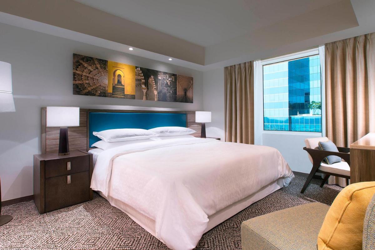 a bedroom with a large bed and a large window at Sheraton Hyderabad Hotel in Hyderabad
