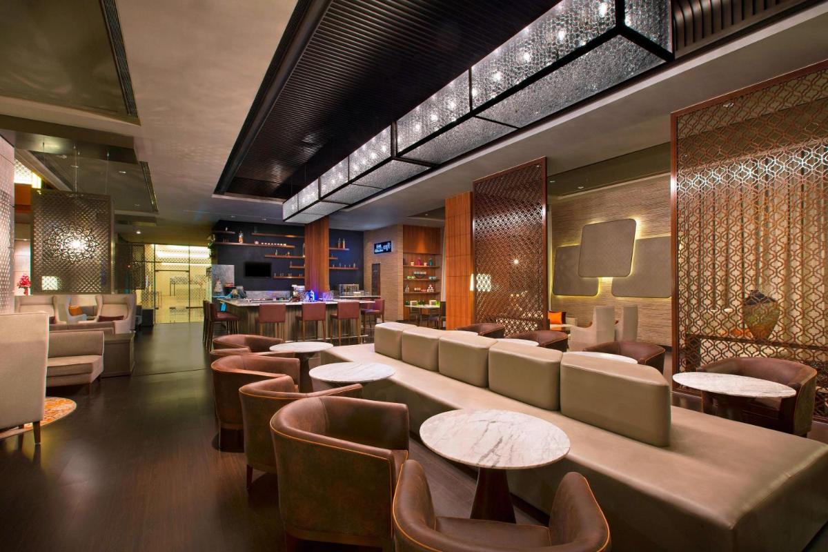 a restaurant with a bar with tables and chairs at Sheraton Hyderabad Hotel in Hyderabad