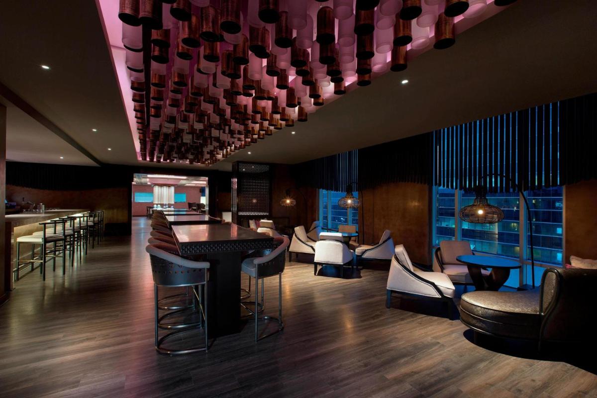 a restaurant with a bar with stools and chairs at Sheraton Hyderabad Hotel in Hyderabad