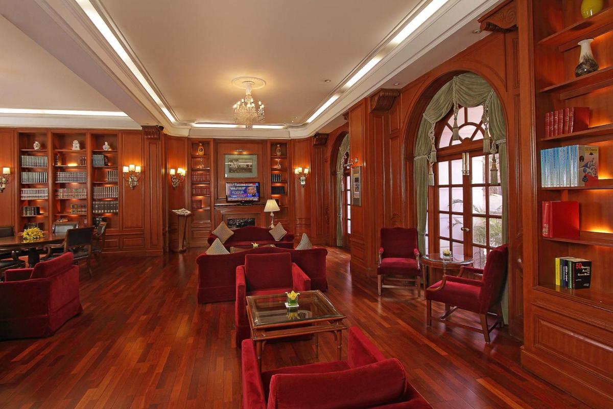 a living room with red furniture and wooden walls at ITC Windsor, a Luxury Collection Hotel, Bengaluru in Bengaluru a living room with red furniture and wooden walls at ITC Windsor, a Luxury Collection Hotel, Bengaluru in Bengaluru
