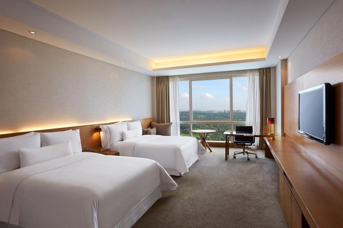 a hotel room with two beds and a flat screen tv at The Westin Mumbai Garden City in Mumbai