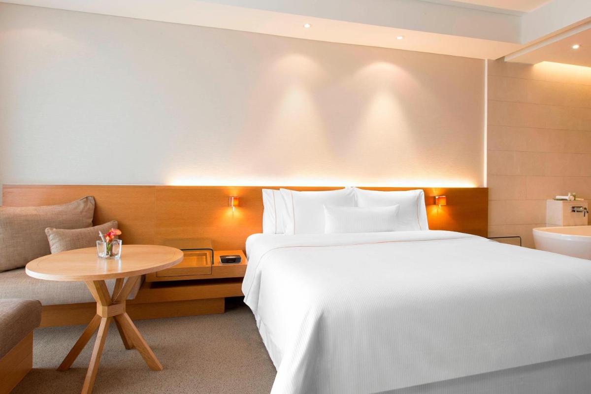 a hotel room with a large bed and a table at The Westin Mumbai Garden City in Mumbai
