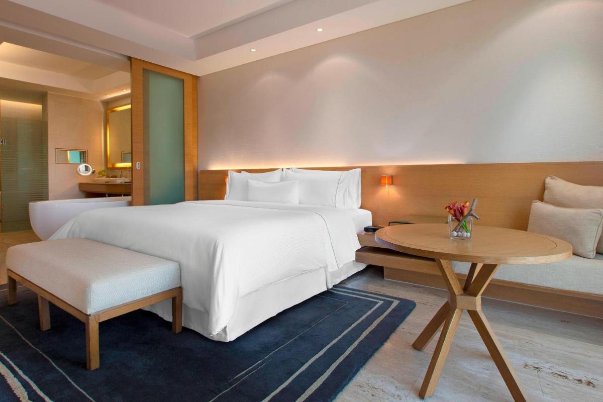 a hotel room with a large bed and a table at The Westin Mumbai Garden City in Mumbai