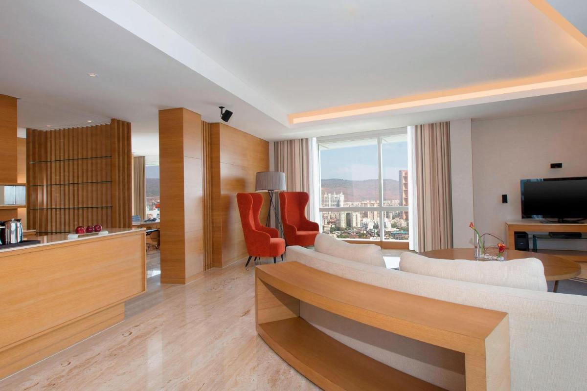 a living room with a couch and chairs and a television at The Westin Mumbai Garden City in Mumbai