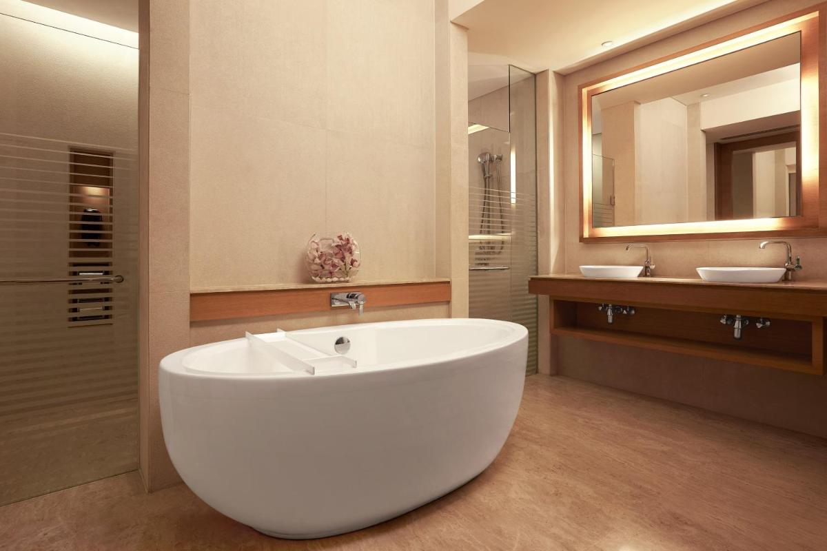a bathroom with a large tub and two sinks at The Westin Mumbai Garden City in Mumbai