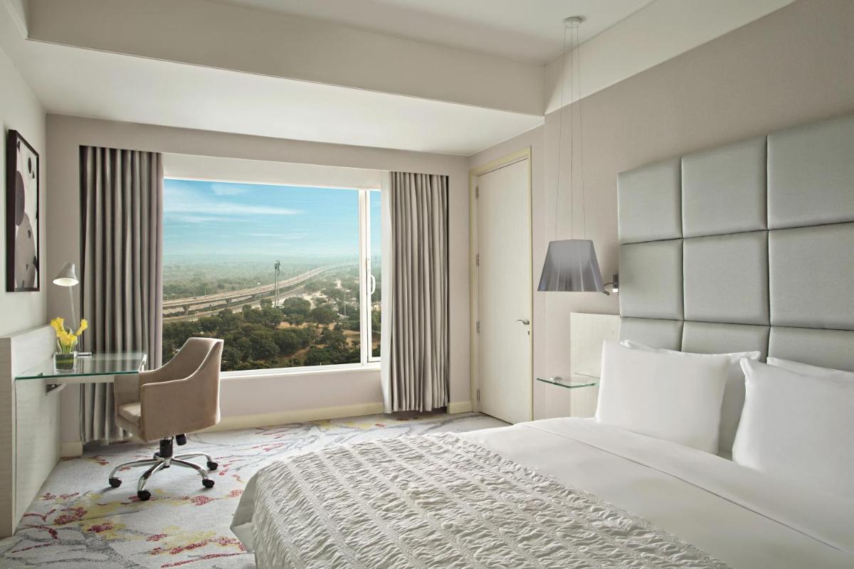 a bedroom with a bed and a desk and a window at Le Meridien Gurgaon, Delhi NCR in Gurgaon a bedroom with a bed and a desk and a window at Le Meridien Gurgaon, Delhi NCR in Gurgaon