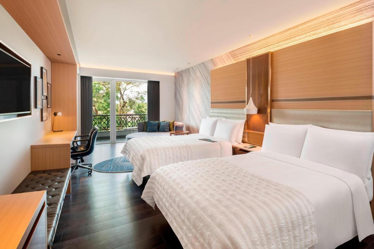 a hotel room with two beds and a television at Le Meridien Goa, Calangute in Calangute a hotel room with two beds and a television at Le Meridien Goa, Calangute in Calangute