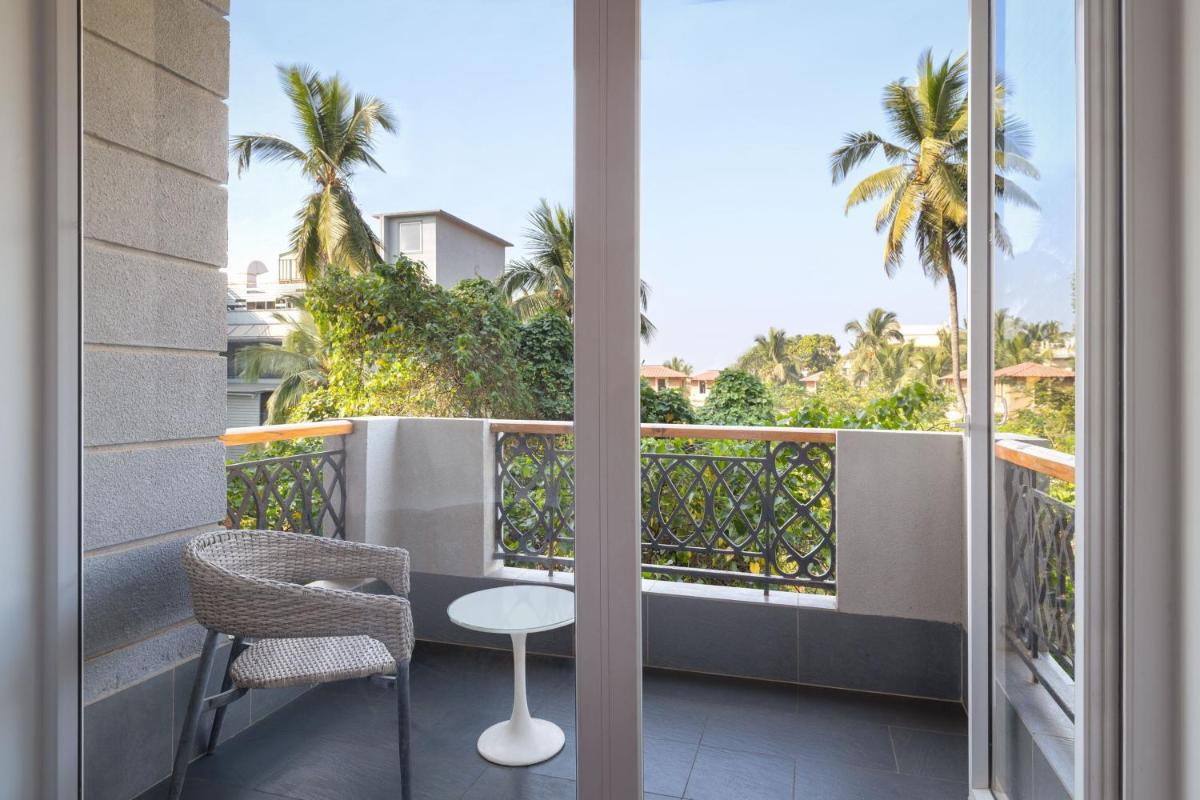 a balcony with a table and chairs and palm trees at Le Meridien Goa, Calangute in Calangute a balcony with a table and chairs and palm trees at Le Meridien Goa, Calangute in Calangute