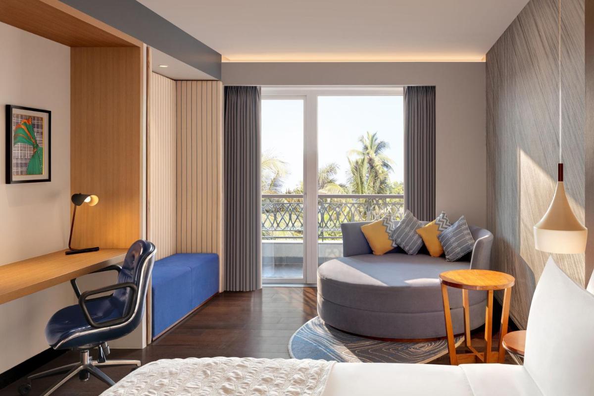a hotel room with a bed and a desk and a couch at Le Meridien Goa, Calangute in Calangute a hotel room with a bed and a desk and a couch at Le Meridien Goa, Calangute in Calangute