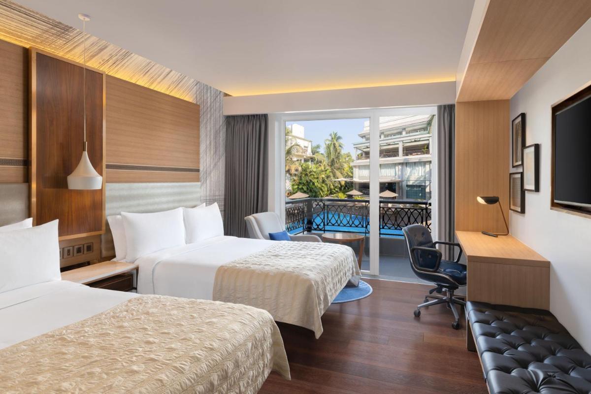 a hotel room with two beds and a desk at Le Meridien Goa, Calangute in Calangute a hotel room with two beds and a desk at Le Meridien Goa, Calangute in Calangute