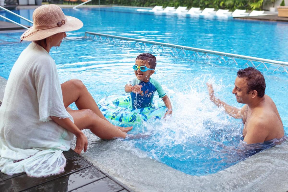 two adults and a child playing in a swimming pool at Le Meridien Goa, Calangute in Calangute two adults and a child playing in a swimming pool at Le Meridien Goa, Calangute in Calangute