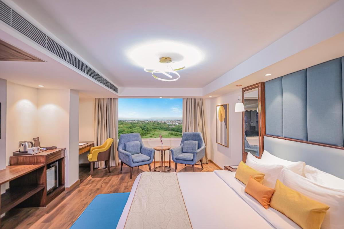 a hotel room with a bed and a desk and chairs at Regenta Dehradun by Royal Orchid Hotels Limited in Dehradun