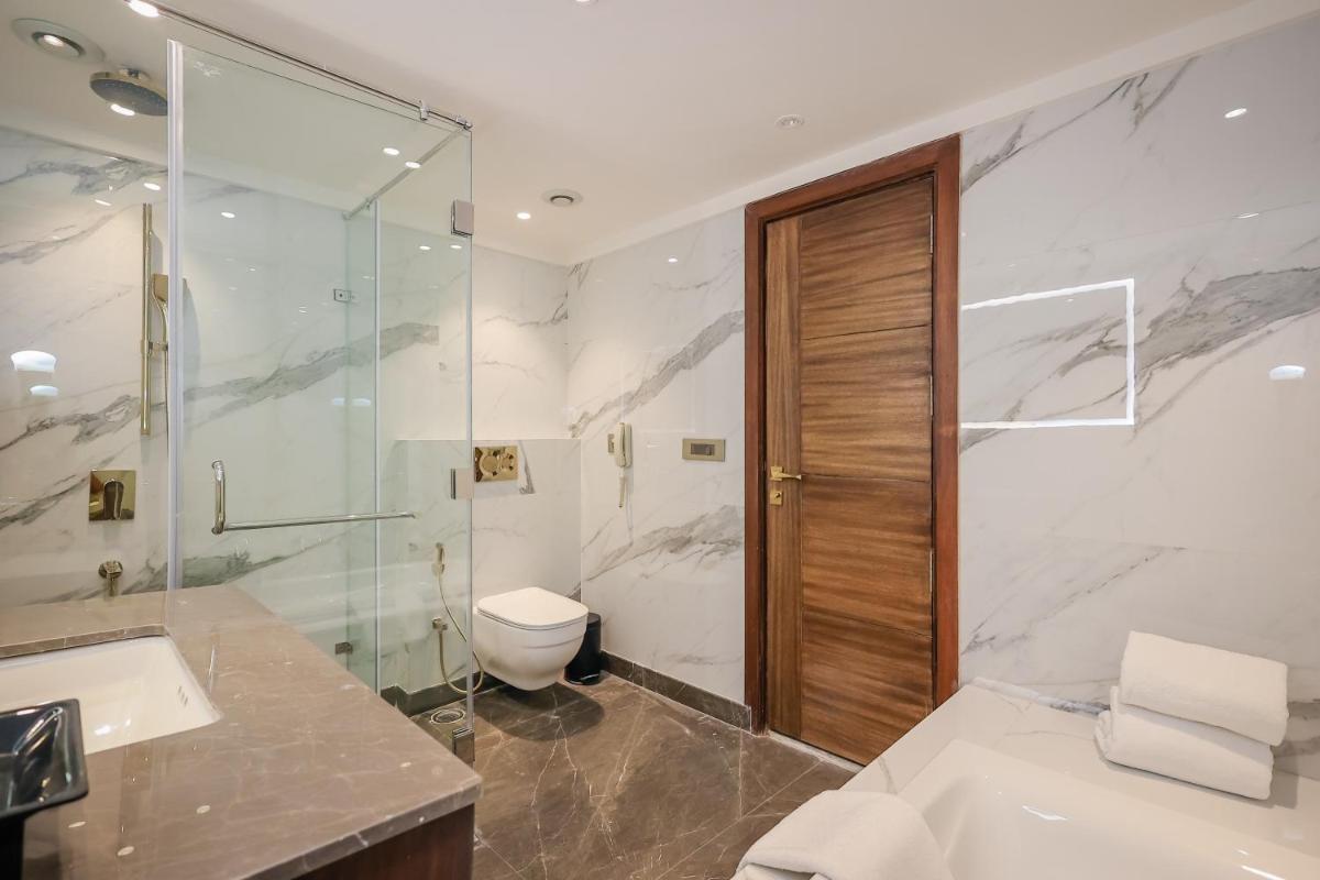 a bathroom with a shower and a toilet and a sink at Regenta Dehradun by Royal Orchid Hotels Limited in Dehradun