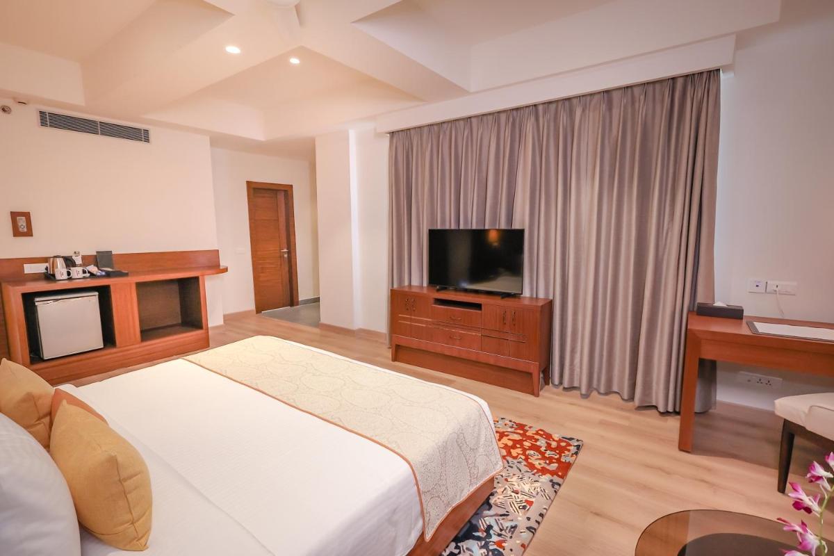 a bedroom with a bed and a flat screen tv at Regenta Dehradun by Royal Orchid Hotels Limited in Dehradun