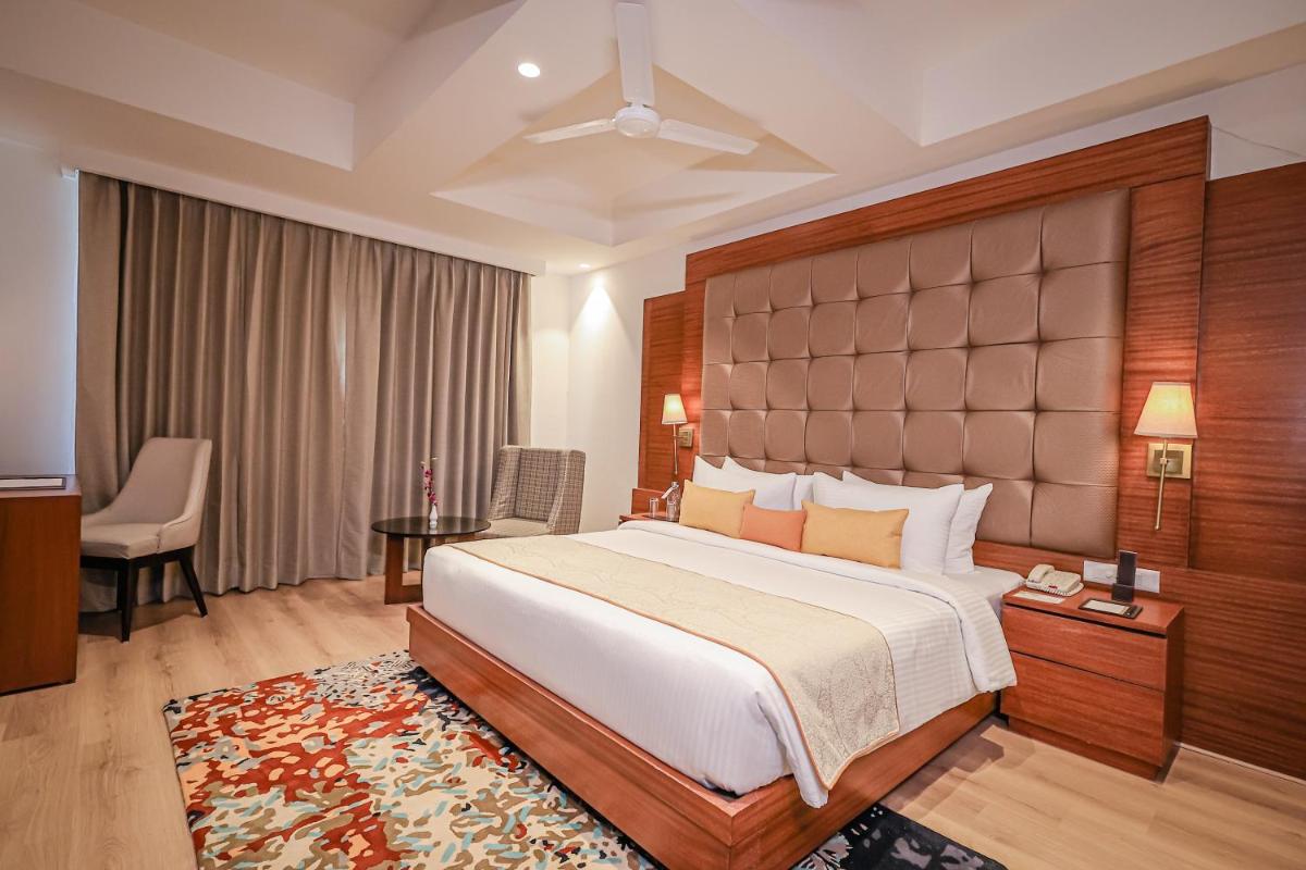 a hotel room with a large bed and a desk at Regenta Dehradun by Royal Orchid Hotels Limited in Dehradun