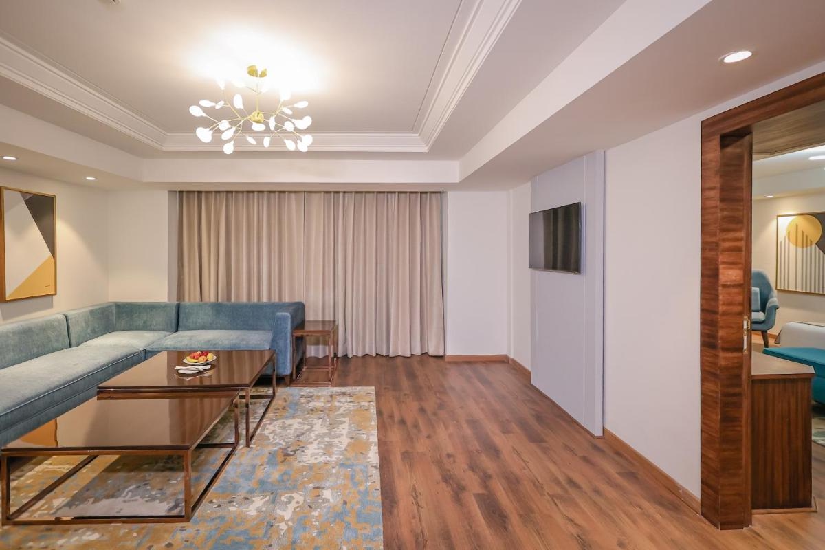 a living room with a blue couch and a table at Regenta Dehradun by Royal Orchid Hotels Limited in Dehradun