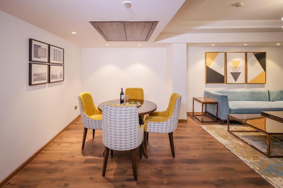 a dining room with a table and chairs and a couch at Regenta Dehradun by Royal Orchid Hotels Limited in Dehradun