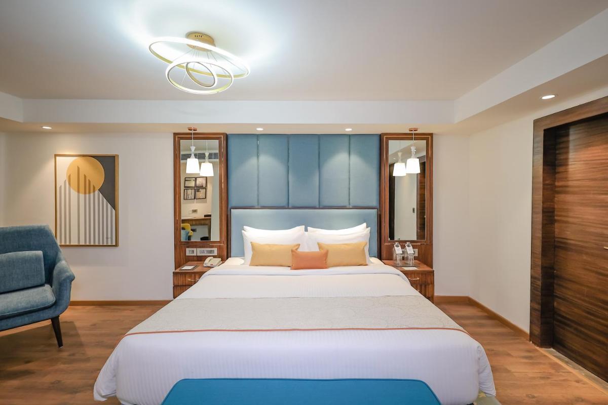 a bedroom with a large bed and a blue chair at Regenta Dehradun by Royal Orchid Hotels Limited in Dehradun