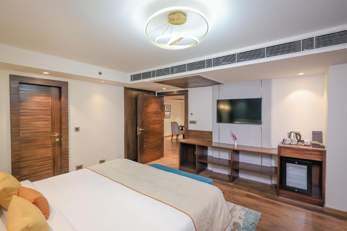 a bedroom with a bed and a desk and a television at Regenta Dehradun by Royal Orchid Hotels Limited in Dehradun