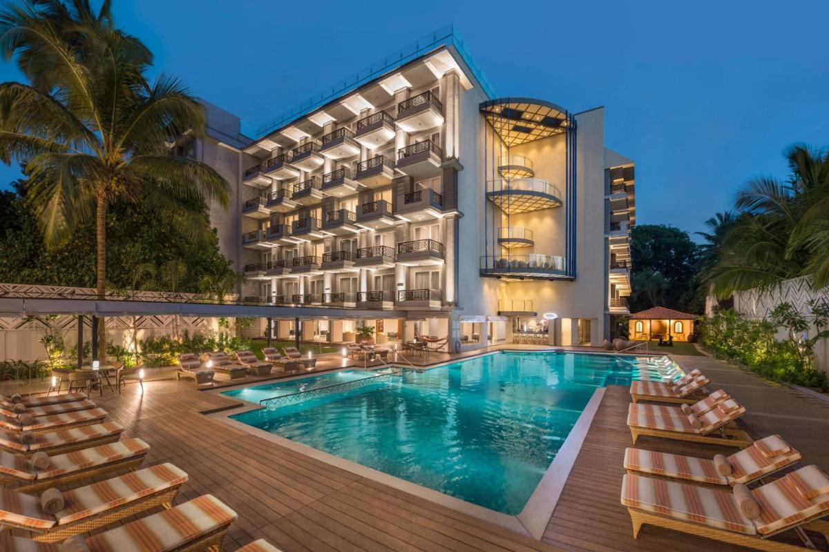 a hotel with a swimming pool and lounge chairs at Le Meridien Goa, Calangute in Calangute a hotel with a swimming pool and lounge chairs at Le Meridien Goa, Calangute in Calangute