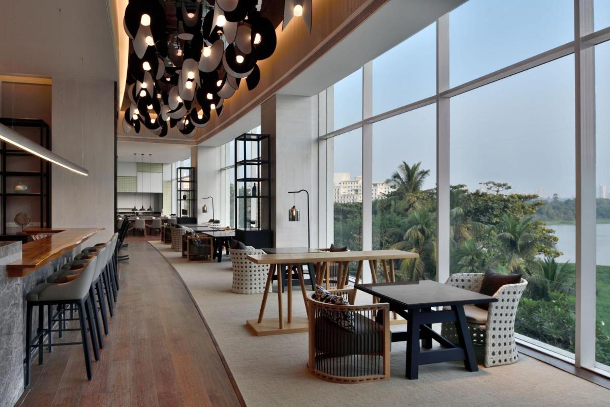 a restaurant with tables and chairs and large windows at The Westin Mumbai Powai Lake in Mumbai