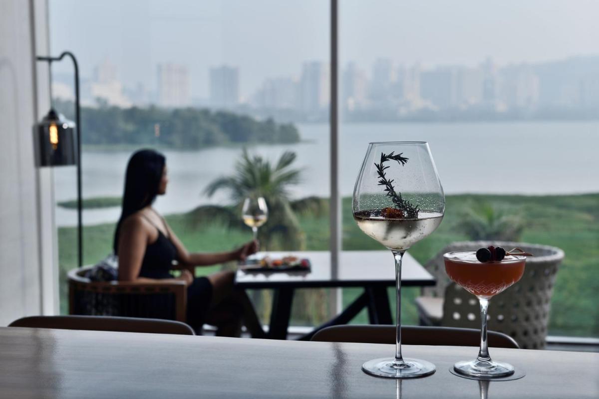 a woman sitting at a table with two glasses of wine at The Westin Mumbai Powai Lake in Mumbai