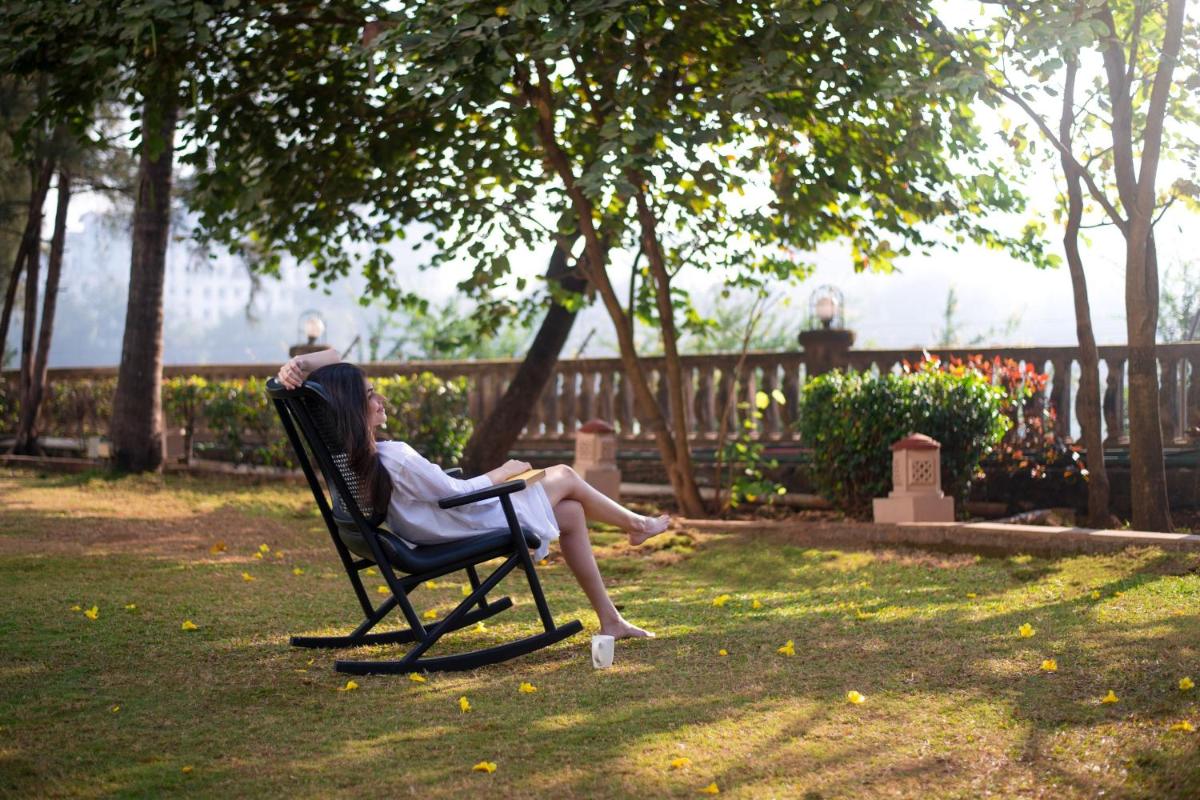 a woman sitting in a chair in the grass at The Westin Mumbai Powai Lake in Mumbai