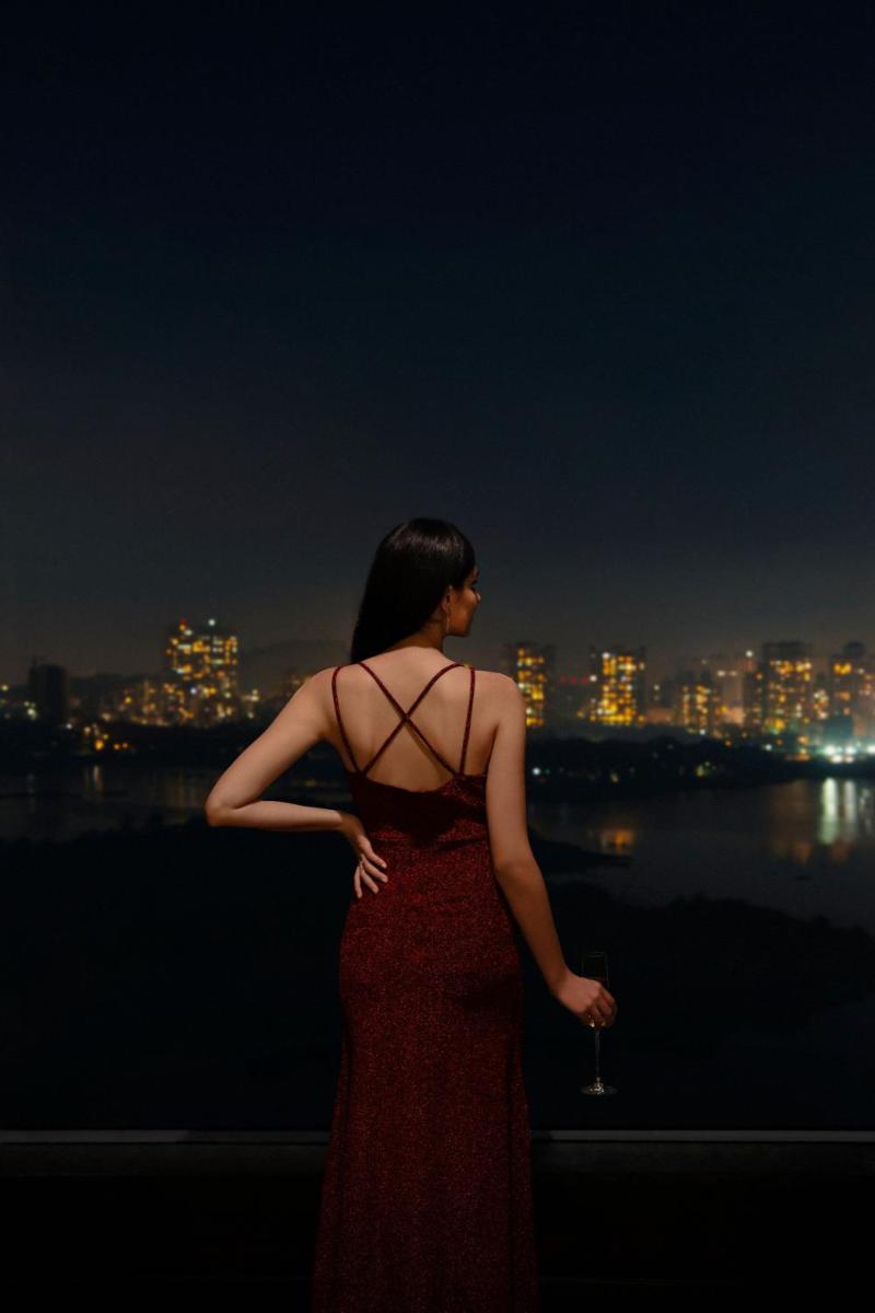 a woman in a red dress looking at the city at night at The Westin Mumbai Powai Lake in Mumbai