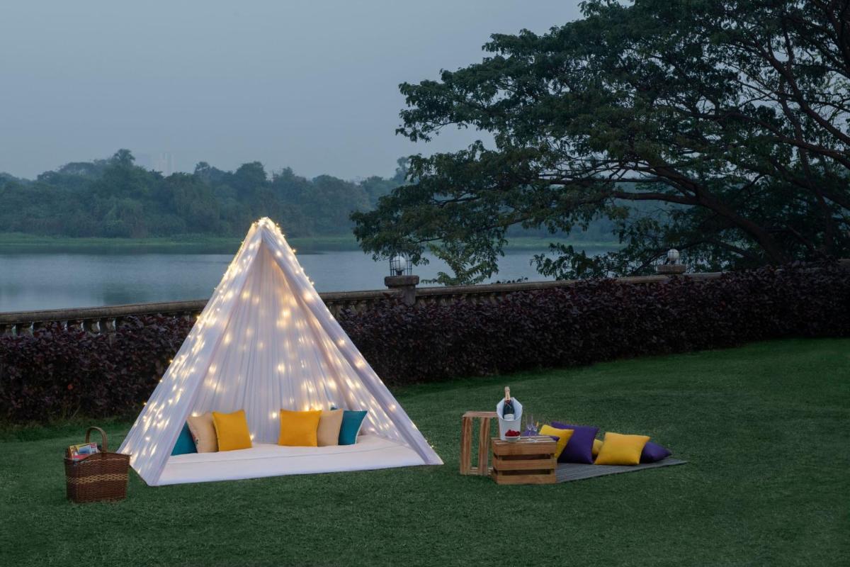 a white tent with pillows and a table on the grass at The Westin Mumbai Powai Lake in Mumbai